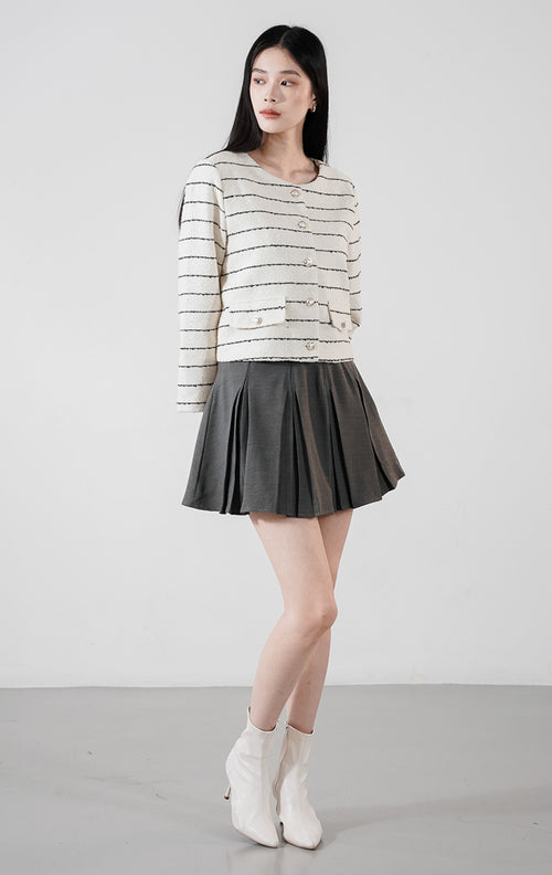 Arianna Top White, blazer crop tweed warna putih dengan motif garis horizontal hitam dan kancing elegan, dipadukan dengan rok plisket.