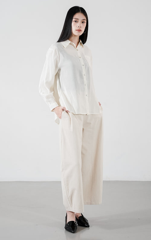 Matea Top warna ivory, kemeja katun lengan panjang dengan siluet bersih, satu saku dada, dan kancing depan minimalis.