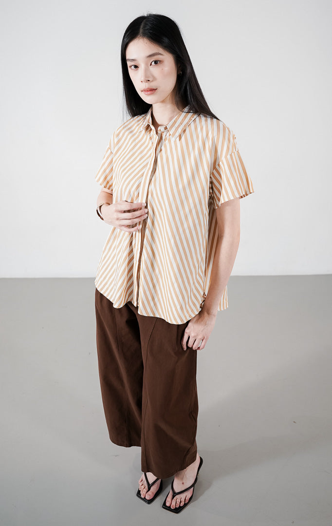 Maxwell Top warna mustard, kemeja lengan pendek motif garis vertikal kuning dan putih dengan kerah klasik dan kancing depan tersembunyi.