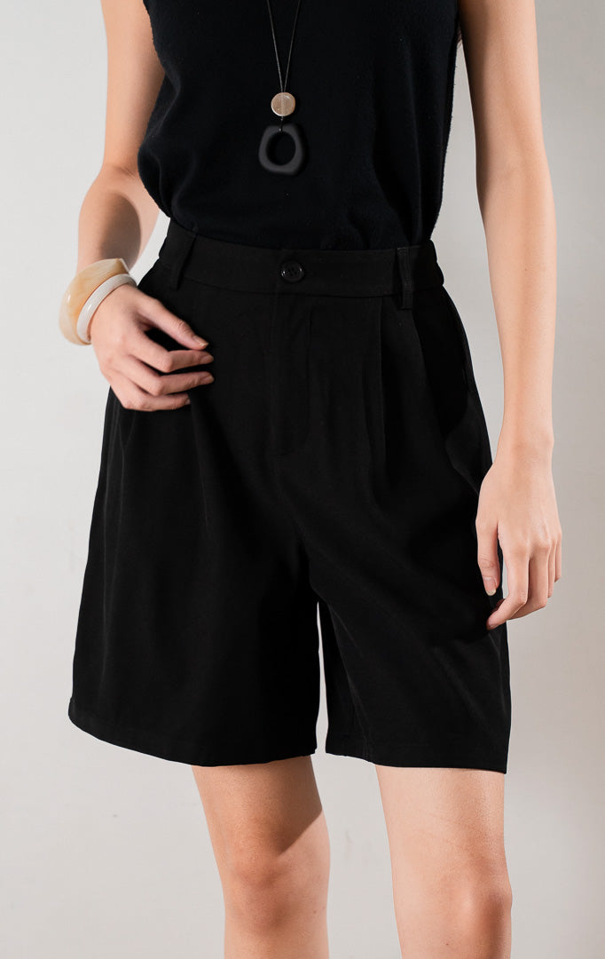 Oliver Pants Black, celana pendek hitam tailored dengan siluet terstruktur, dipadukan dengan tank top hitam dan heels cokelat