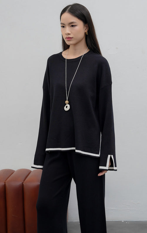 Setelan wanita atasan dan bawahan berbahan rajut lembut (soft stretchy knit) warna hitam dengan motif garis (striped pattern), detail belahan samping (subtle slit), dan pinggang karet elastis.