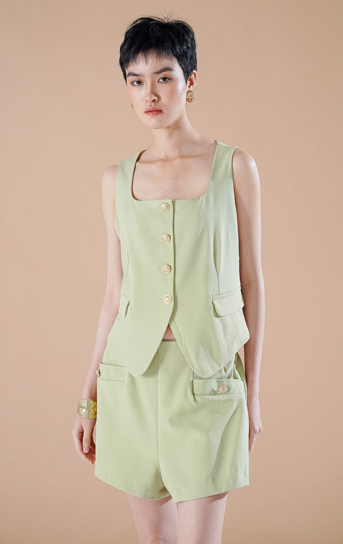 Setelan wanita Pepper Set warna Sage Green yang terdiri dari blazer tanpa lengan terstruktur dengan kancing depan dan celana pendek senada.