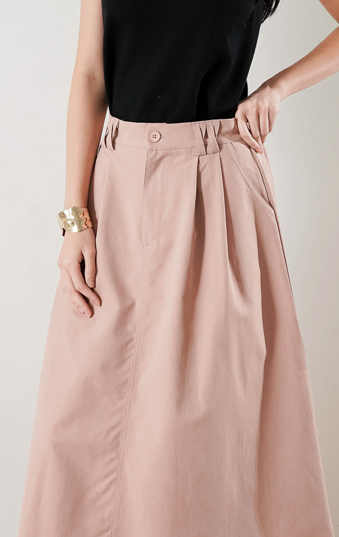 Rafaela Skirt Dusty Pink, rok panjang A line dengan detail lipit (pleats) di bagian depan, dipadukan dengan atasan hitam dan sepatu flat glitter.