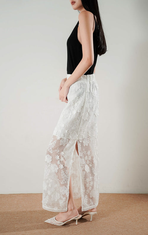 Safiya Skirt White, rok panjang putih dengan detail bordir bunga transparan yang mewah, dipadukan dengan tank top hitam.