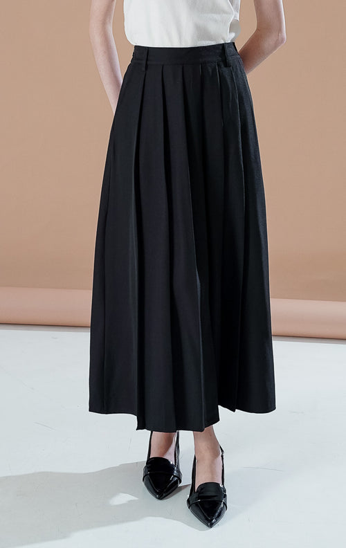 Sonali Skirt Black, rok panjang hitam dengan detail lipit (pleats) yang mengalir, saku depan fungsional, dan ban pinggang yang rapi