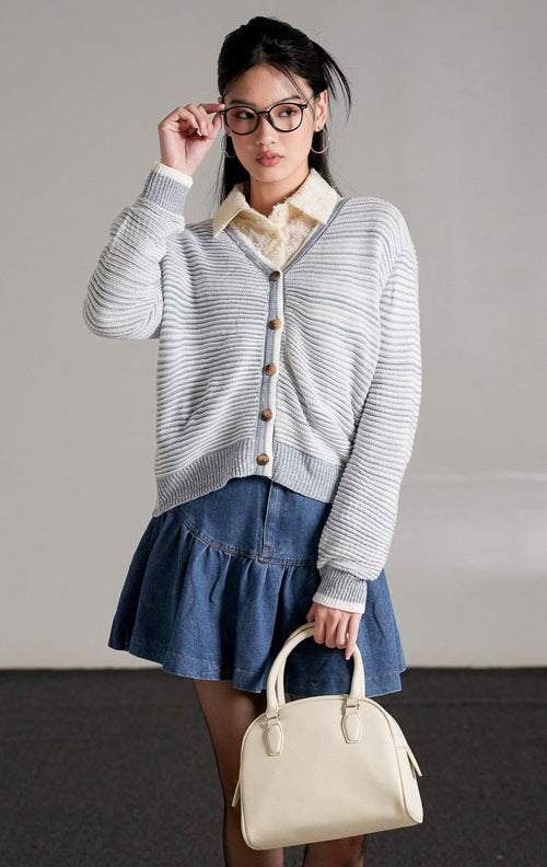 Aderyn Two-Tone Knit Cardigan abu-abu putih berbahan rajut yang dipadukan dengan celana jeans biru.
