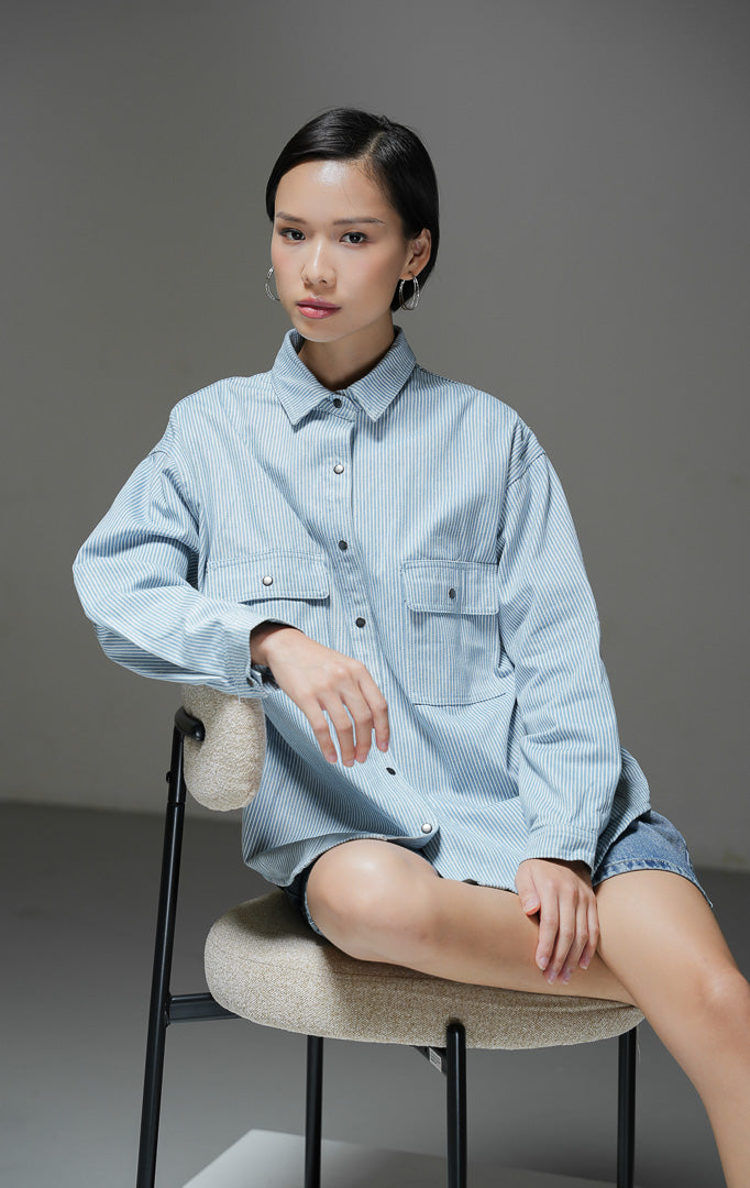 Kemeja jeans wanita Adriana Top warna light denim stripe motif garis salur biru muda lengan panjang dengan dua saku depan dan kancing kemeja.