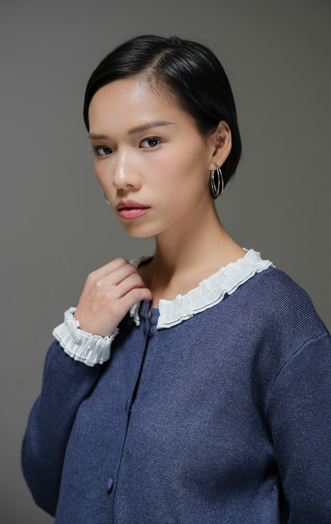 Cardigan rajut wanita Aiko Top warna navy biru dongker lengan panjang dengan aksen renda putih pada kerah bulat dan bagian bawah hem.
