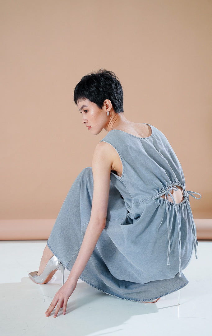 Alexandra Dress Light Blue, gaun denim panjang tanpa lengan dengan detail cut out menawan dan tali serut pada bagian punggung
