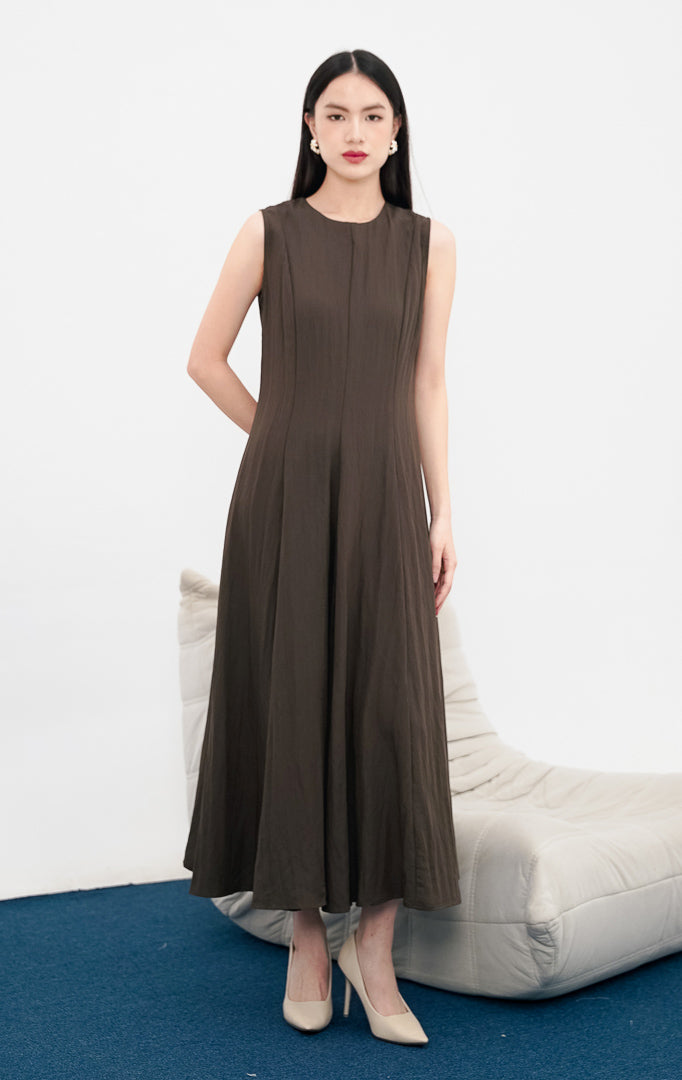 Model wanita mengenakan Callan Dress warna dark brown, gaun maxi tanpa lengan (sleeveless) dengan siluet minimalis dan potongan kerah bulat yang elegan.