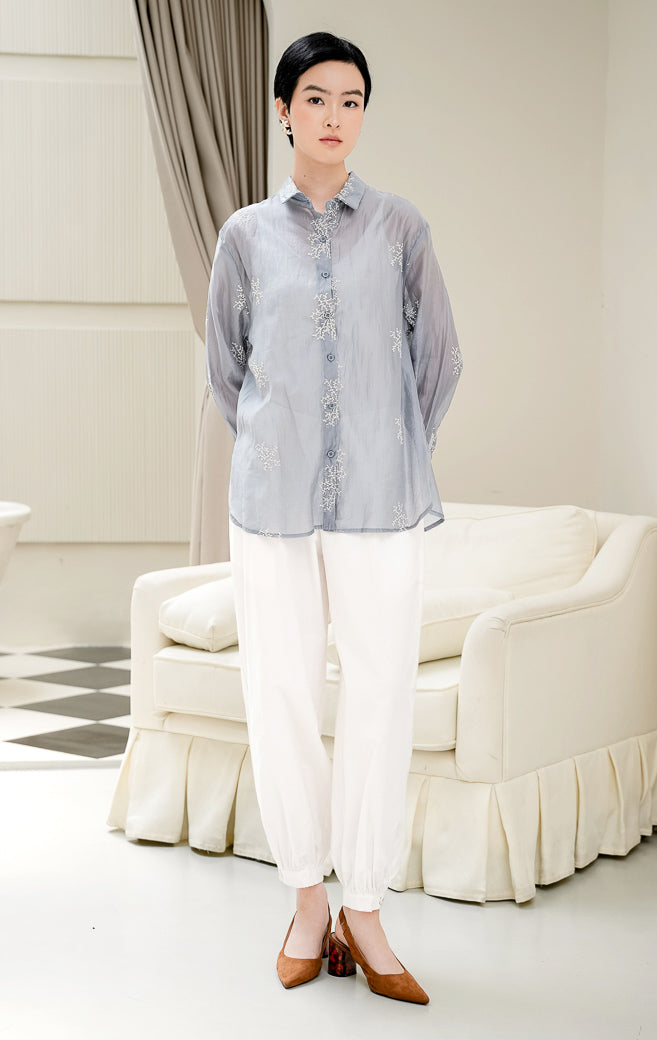 Atasan kemeja wanita Amaranth Top warna dusty blue berbahan cotton voile transparan (sheer) dengan motif bordir (embroidery) dan kancing depan style feminine & elegant.