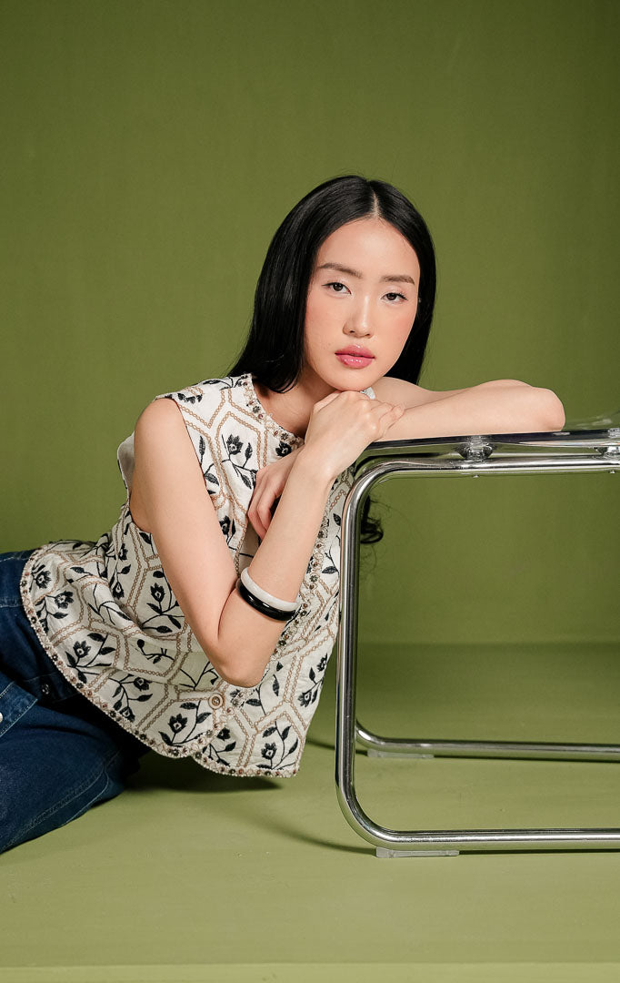 Atasan wanita Anne Top warna ivory tanpa lengan dengan kancing depan, dihiasi pola bordir bunga warna gelap di dalam bingkai geometris, serta pinggiran manik-manik.