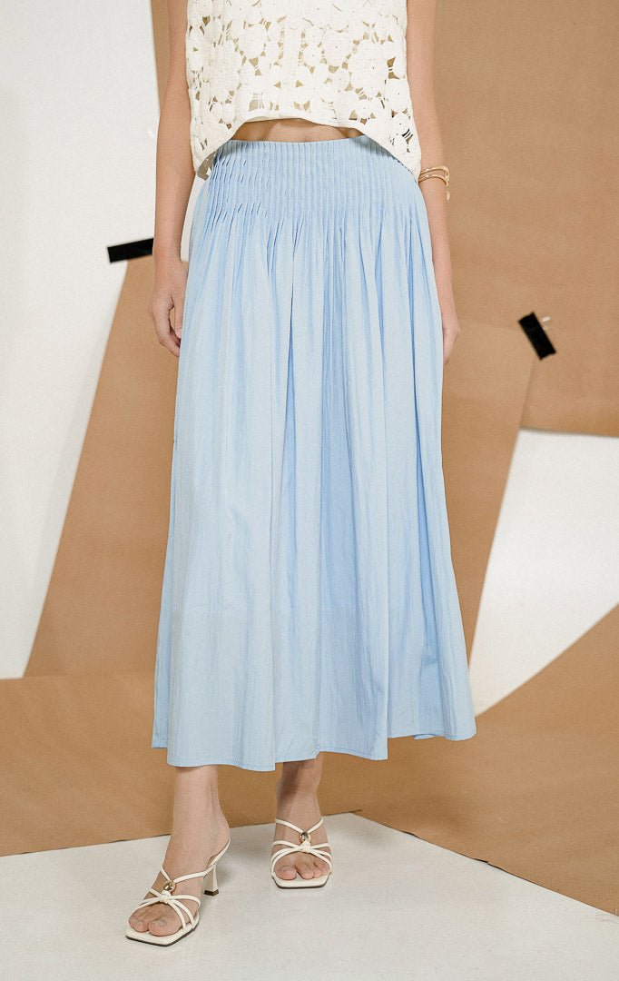 Close up detail pinggang karet elastis dan jahitan rempel dari Annora Skirt Light Blue, produk rok maxi panjang wanita warna biru muda dipadukan dengan atasan rajut putih.