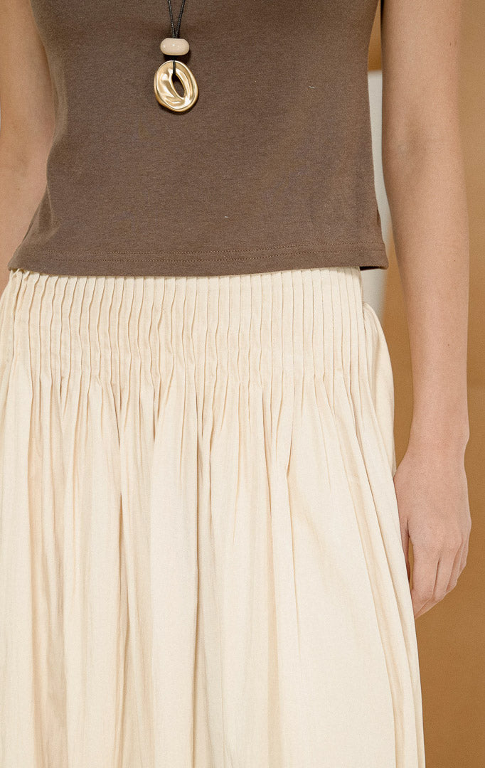 Close up detail pinggang karet elastis dan jahitan rempel dari Annora Skirt Yellow, produk rok maxi panjang wanita warna kuning pastel lembut dipadukan dengan atasan cokelat.