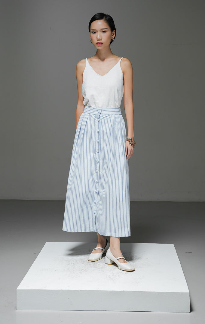 Rok midi wanita Artemis Skirt warna light blue biru muda motif salur garis vertikal dengan kancing depan berlaput kain, detail pleat, dan pinggang karet.