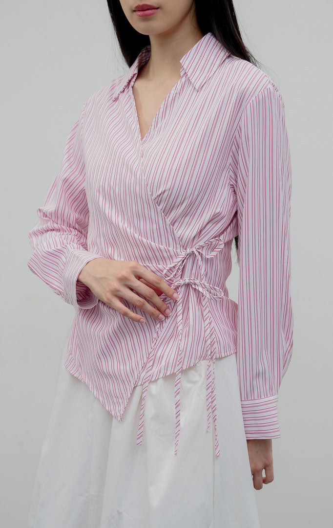 Kemeja wanita lengan panjang warna merah muda (pink) Audreyna Top berbahan campuran katun-poliester terstruktur dengan kerah V-neck, aksen ikatan tali pita (tie detail), dan bukaan kancing depan.