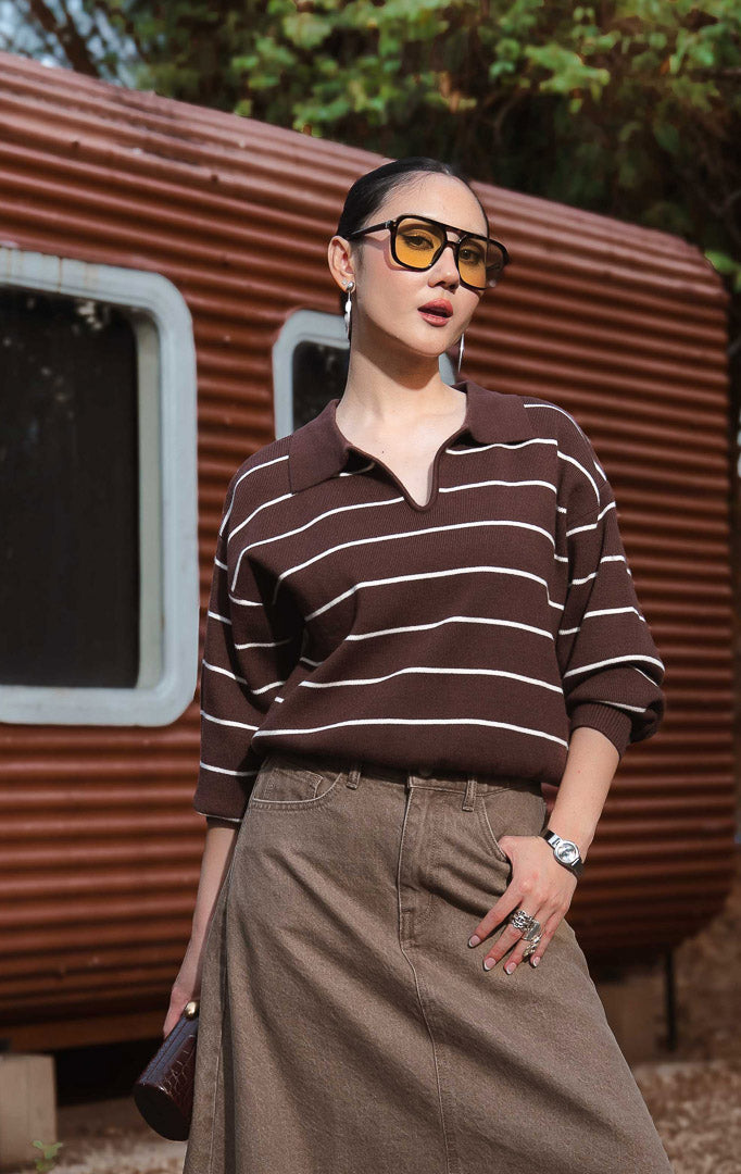 Sweater rajut wanita lengan panjang motif garis warna cokelat tua (dark brown striped knit sweater) Grifina Sweater dengan siluet longgar santai (relaxed slouchy silhouette), kerah polo V-neck, dan bahan rajut elastis (stretchy knit).