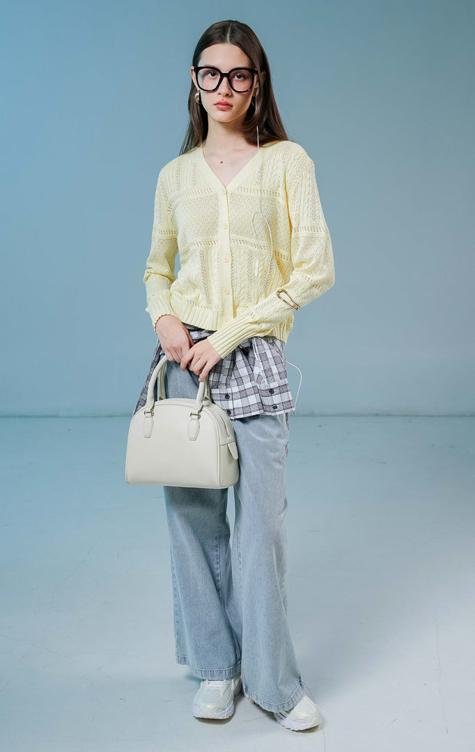 Model wanita mengenakan Wilder Cable Knit Pointelle Cardigan warna butter yellow, luaran cardigan rajut wanita leher V-neck berwarna kuning muda dengan perpaduan motif rajut kepang dan lubang mikro anggun.
