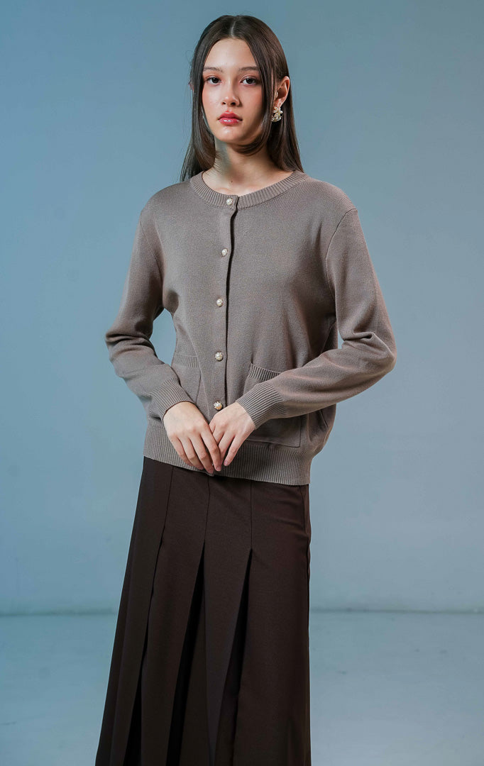 Model wanita mengenakan Ellington Knit Cardigan warna coklat muda, luaran rajut wanita berkerah bulat dengan detail kancing depan elegan dan saku.