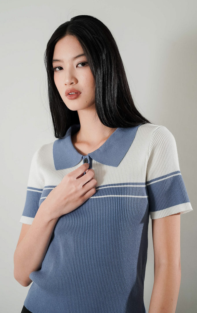 Atasan rajut lengan pendek berkerah Carmen Top bergaya dua warna putih dan dusty blue dengan detail kancing depan, dipadukan dengan celana kulot panjang berwarna hitam.