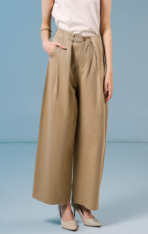 Model wanita mengenakan Normandy Pleated Straight Pants warna khaki, celana panjang bahan katun wanita dengan detail lipit depan dan potongan straight-leg.