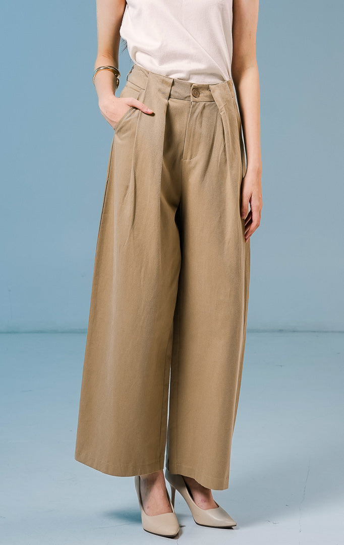 Model wanita mengenakan Normandy Pleated Straight Pants warna khaki, celana panjang bahan katun wanita dengan detail lipit depan dan potongan straight-leg.