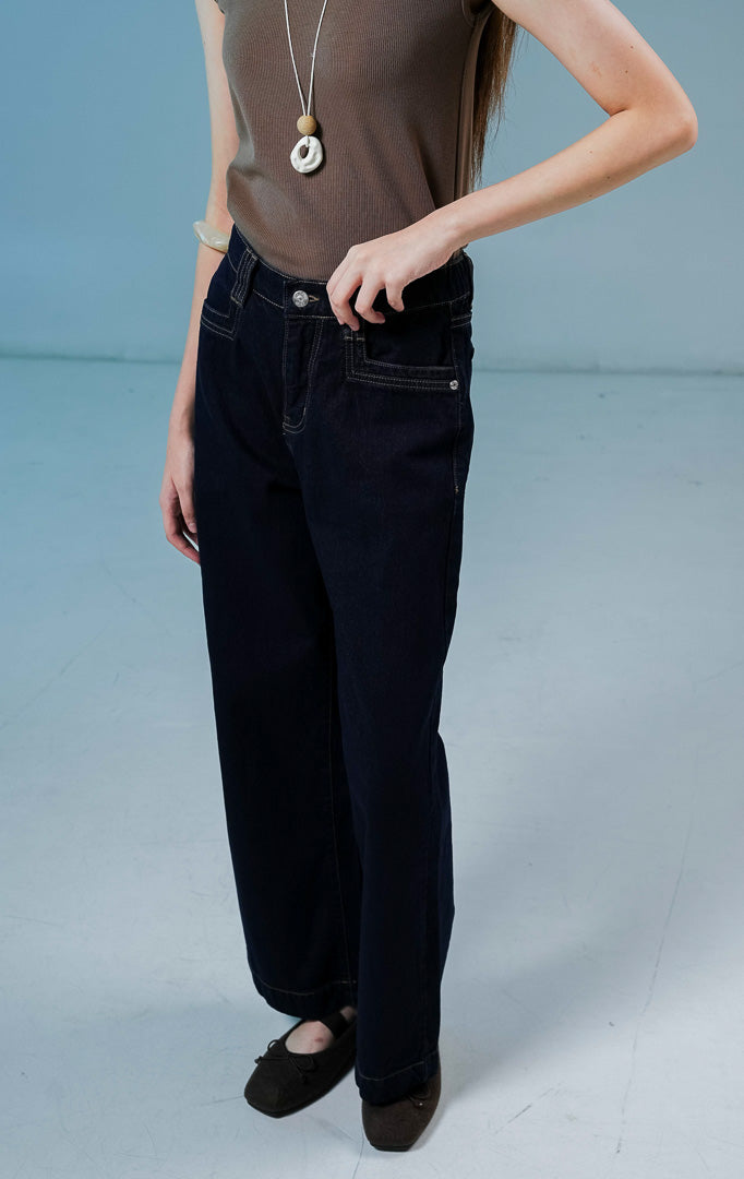 Model wanita mengenakan celana jeans Anaide Straight-Leg Pants warna dark denim berpotongan lurus dengan saku dan kancing depan.