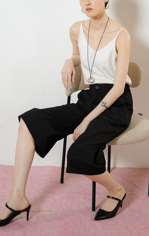 Model wanita duduk mengenakan Roderick Cropped Culottes Pants warna black, celana kulot gantung wanita bahan katun twill warna hitam dengan potongan sebetis.