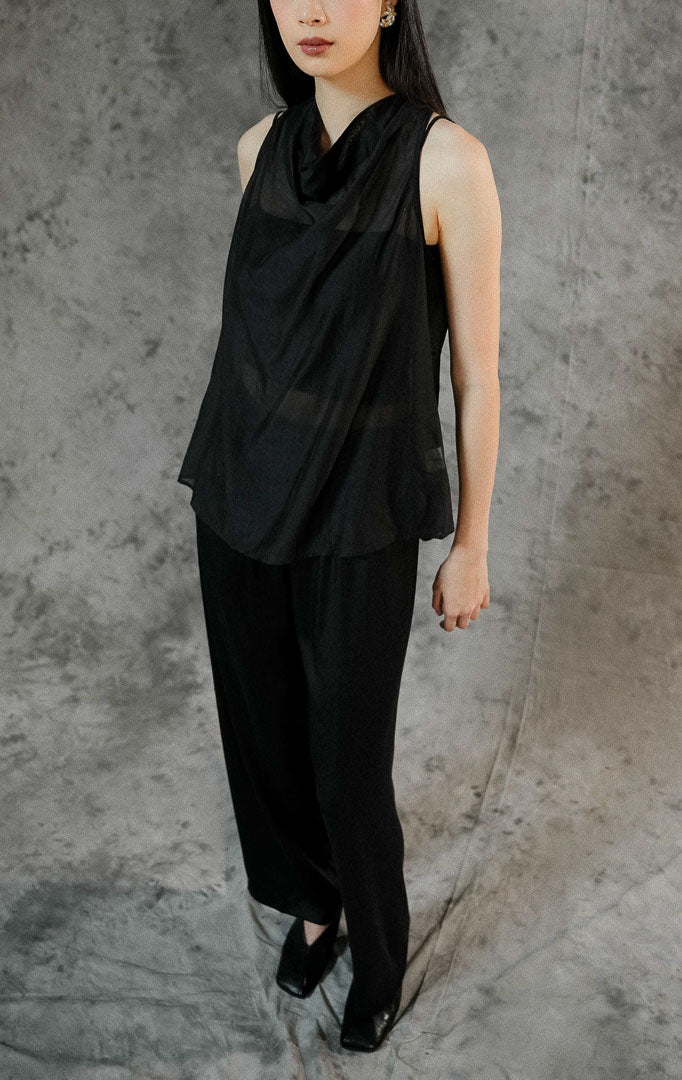 Blouse wanita tanpa lengan Charlette warna hitam polos dengan bahan transparan (sheer) yang elegan, cocok dipadukan dengan inner untuk look semi-formal.