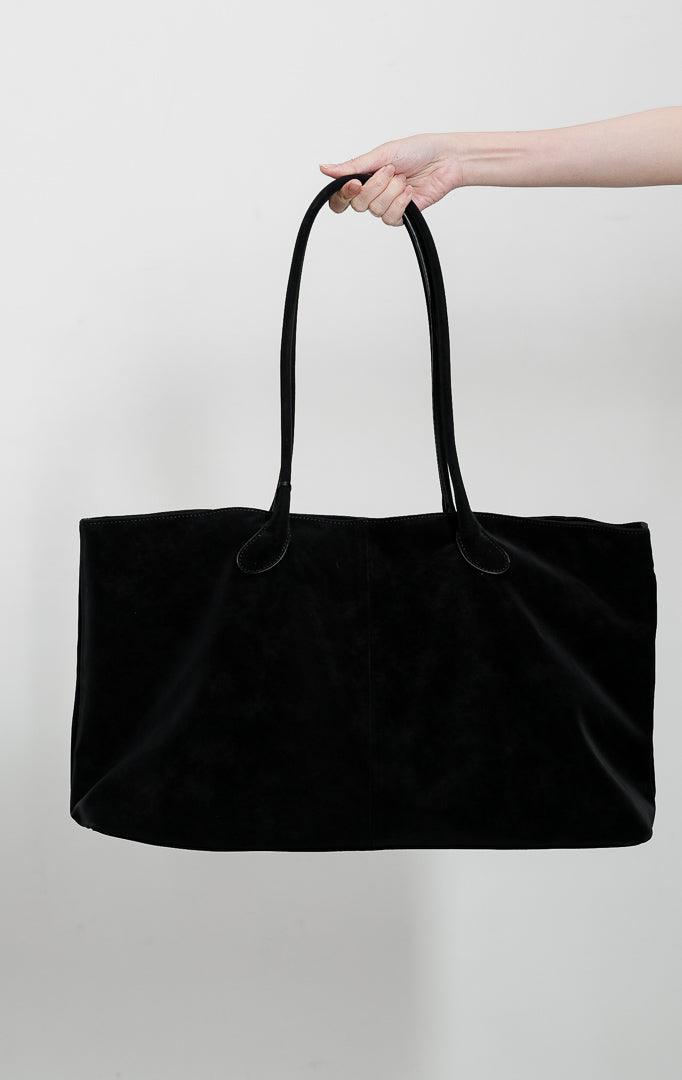 Tas tote wanita Chiro warna hitam pekat menampilkan siluet lebar terstruktur berbahan suede premium lembut dengan dua tali bahu panjang melengkung (double shoulder strap).