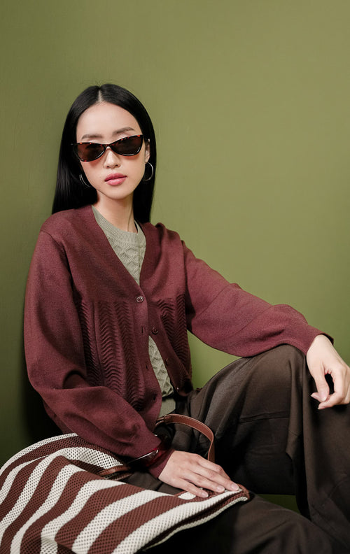 Kardigan rajut wanita Daliya Cardigan warna cokelat tua (dark brown) polos dengan kerah V-neck, kancing depan, dan detail tekstur rajutan bermotif gelombang pada area depan bawah.