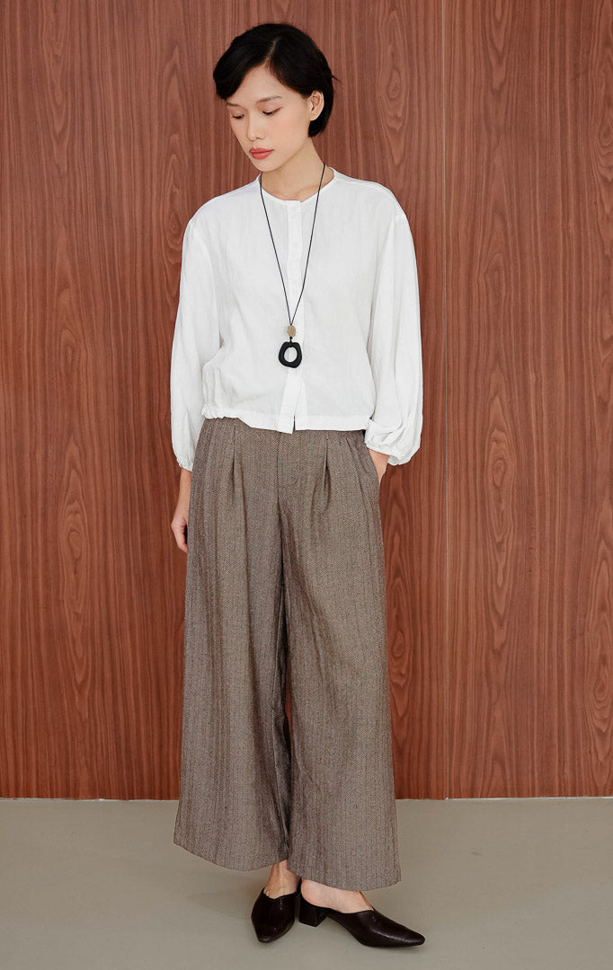 Atasan blus wanita warna putih Damian Top berbahan katun ringan dengan kerah bulat, kancing depan, lengan panjang balon (puff sleeve), dan kelim karet (elastic hem).