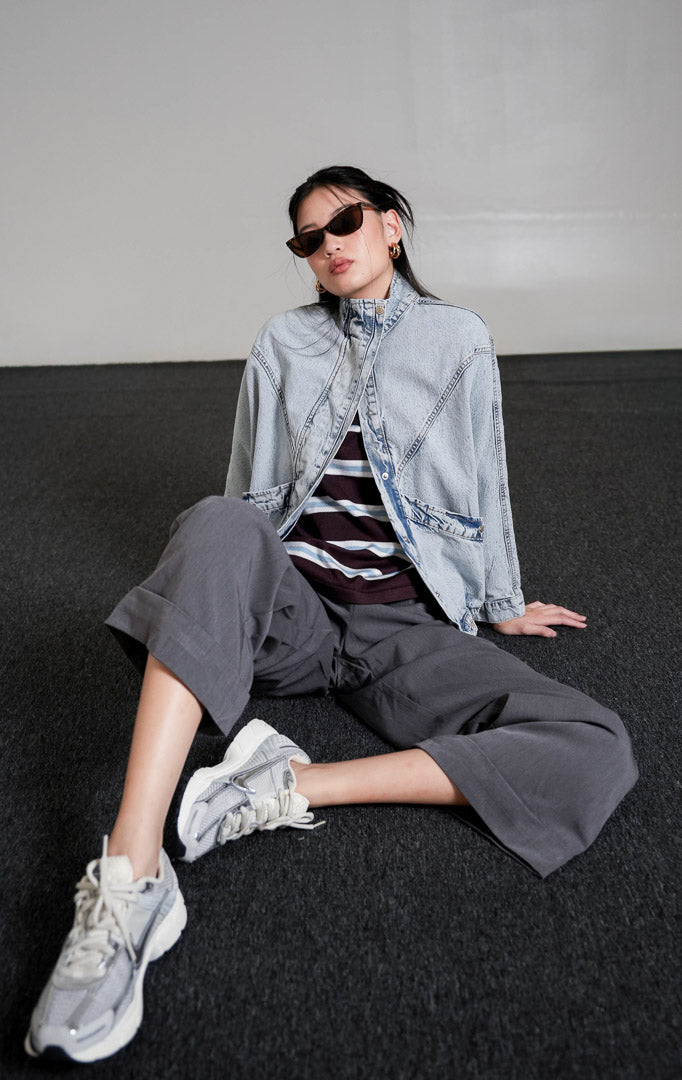 Derry Oversized Jacket warna light denim (biru muda) dengan detail kerah tinggi dan saku depan, dipadukan bergaya denim-on-denim dengan celana jeans senada dan sneakers.