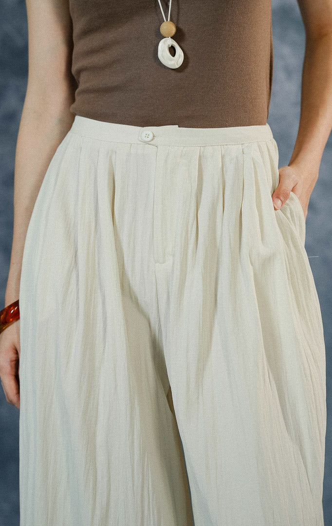 Celana panjang wanita Echo warna ivory dengan cutting loose pants kulot, berbahan crinkle-polyester flowy, dilengkapi saku samping dan resleting depan.