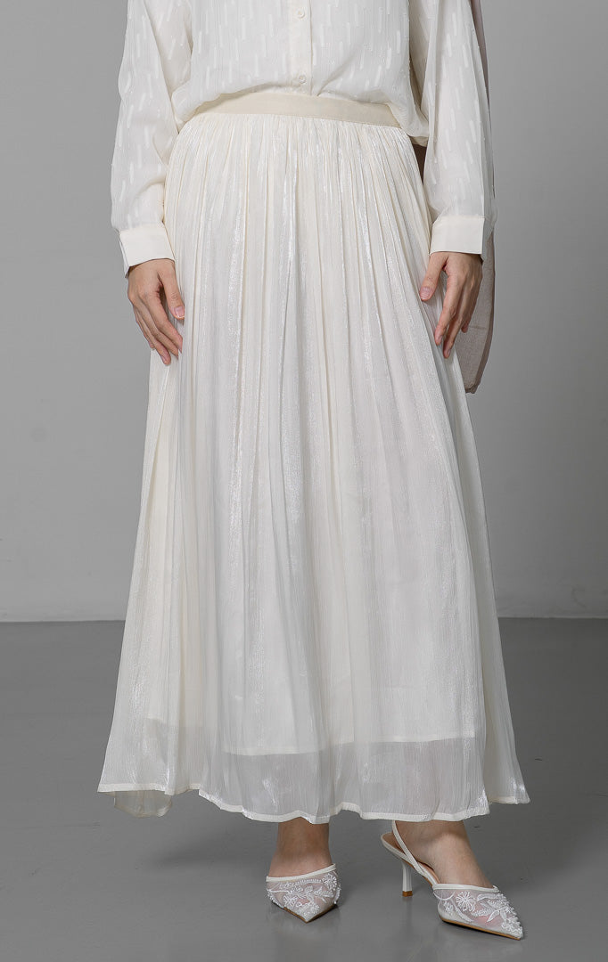 EID Anais Skirt Ivory, rok panjang wanita model A line warna putih gading
dengan efek shimmer lembut, pinggang karet kerut, dan potongan flowy
yang elegan.