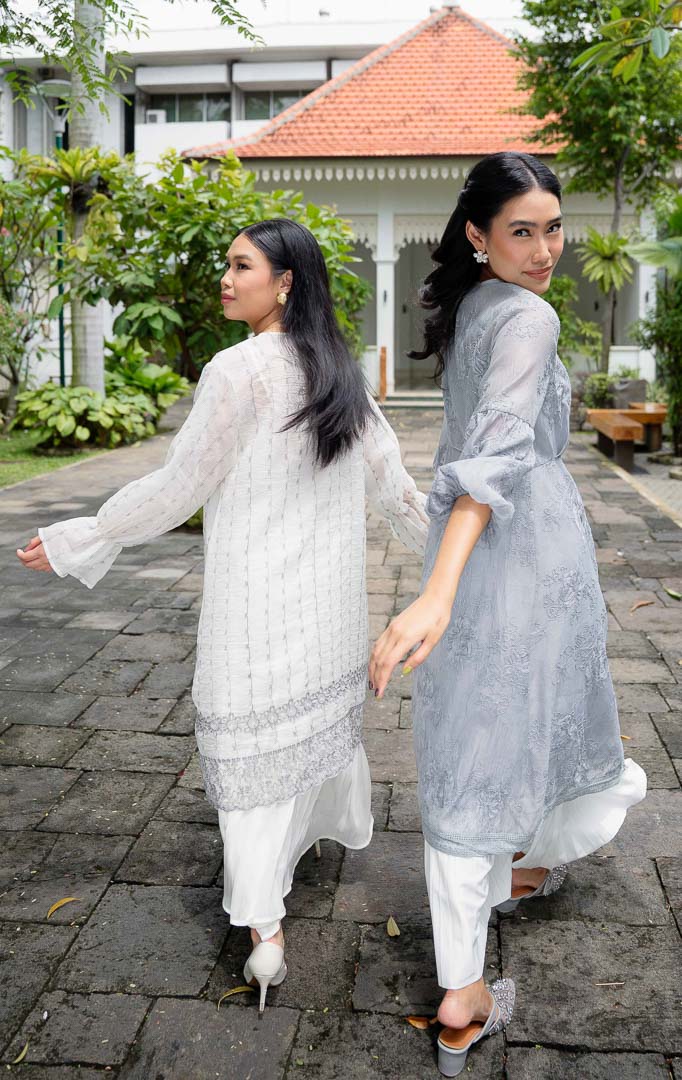 Model mengenakan EID Aniza Top Grey, atasan wanita bahan cotton
organza warna abu abu transparan dengan motif bordir bunga vertikal dan
ujung lengan model flare