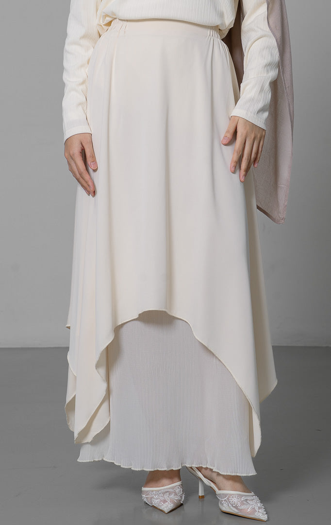 EID Atelier Skirt Ivory, rok bawahan wanita warna putih gading dengan
desain tumpuk layer, bagian dalam bahan plisket lipit dan bagian luar
bahan polos dengan potongan asimetris melengkung.
