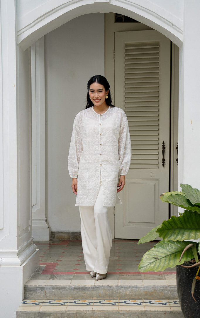 EID Garini Outer Ivory, atasan tunik wanita bahan cotton voile warna putih
gading dengan motif bordir eyelet geometris horizontal dan deretan
kancing emas depan