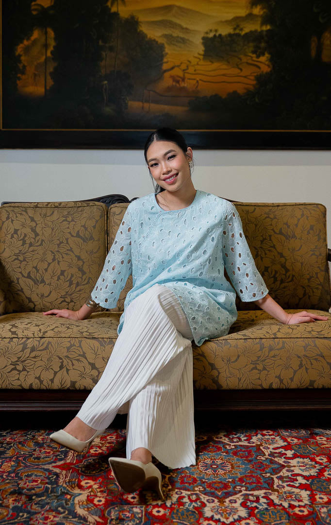 EID Latifa Top Blue, atasan wanita warna biru muda bahan katun dengan
motif bordir eyelet berlubang dan detail kancing mutiara miring asimetris di
bagian depan.