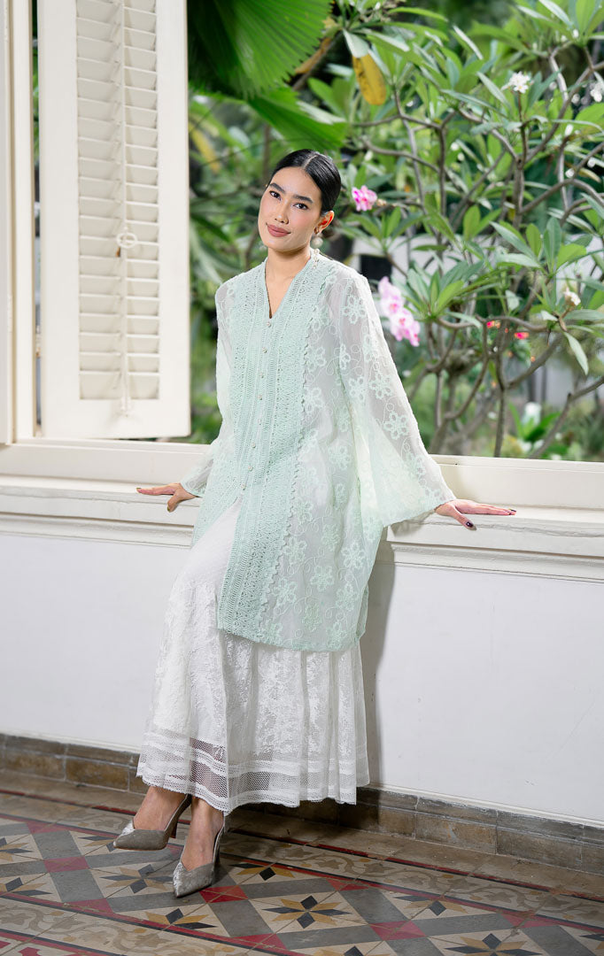 EID Naseha Top Sage, atasan blouse wanita warna hijau sage bahan cotton
voile transparan dengan motif bordir bunga dan detail panel renda lace
vertikal lebar di depan