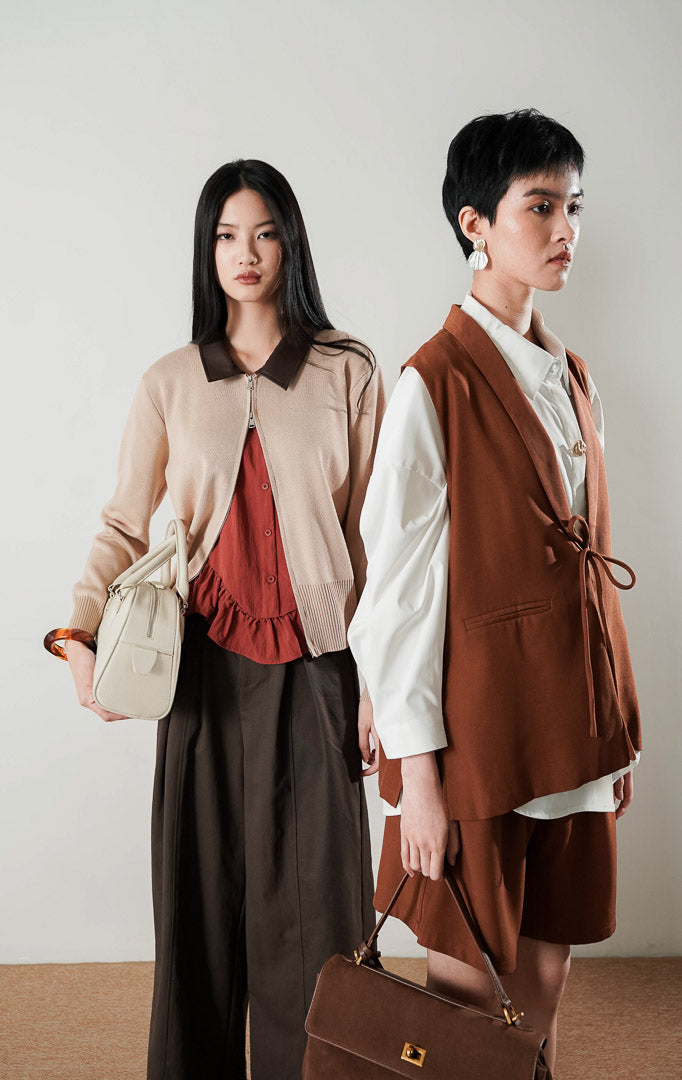 Eliana Sweater Khaki, atasan rajut warna krem dengan ritsleting depan dan detail kerah kulit berwarna cokelat tua, dipadukan dengan celana kulot lebar cokelat.