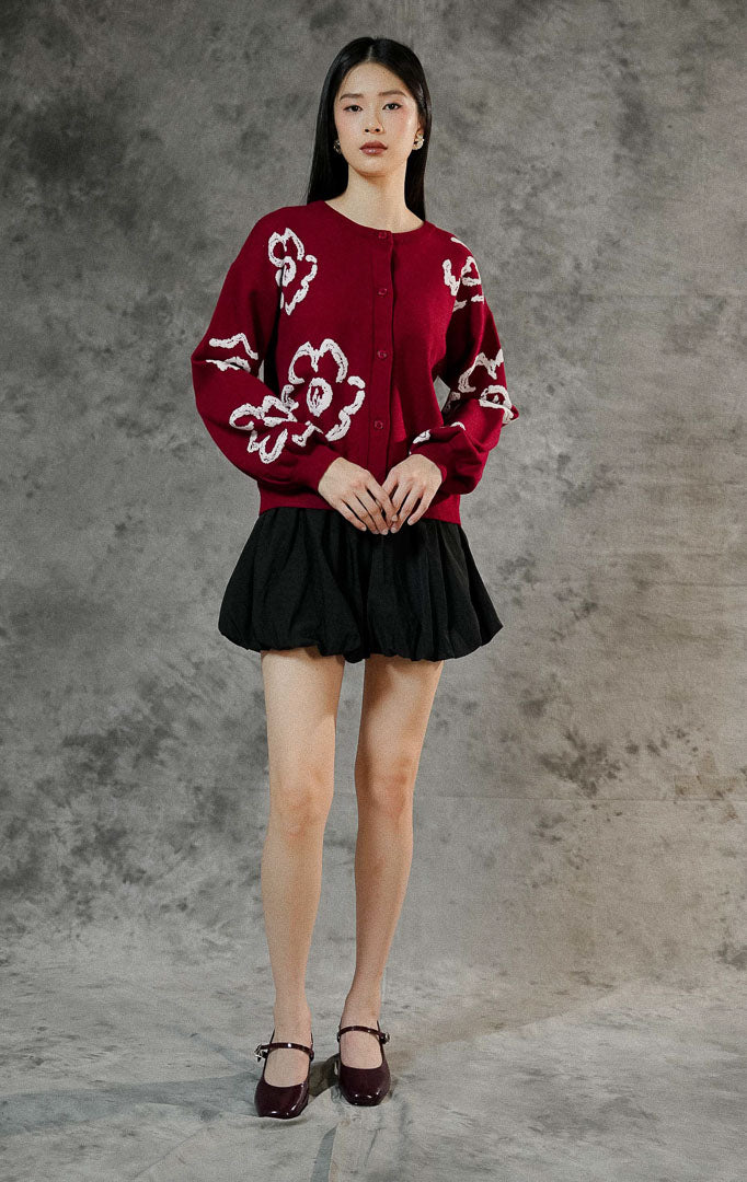 Kardigan rajut wanita Emmelie warna maroon lengan panjang dengan motif bunga (floral), berkerah bulat, kancing depan, dan ujung lengan karet elastis.