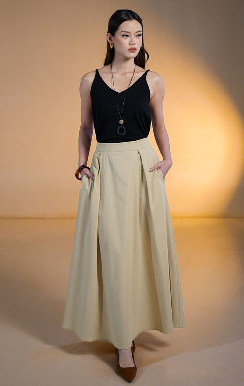 Model wanita memakai Estelle Skirt Khaki, rok midi potongan A-line lebar bahan katun warna beige/khaki dengan saku samping dan atasan hitam