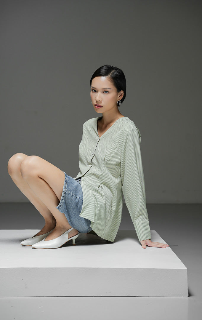 Atasan wanita Finnegan Top warna light green motif pinstripe salur halus dengan kerah V-neck, lengan panjang, dan kancing depan.