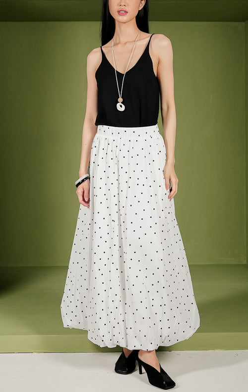 Rok midi wanita Florence Skirt siluet balon bervolume warna putih dengan motif polka dot hitam kecil di seluruh bagian, dilengkapi dengan pinggang karet elastis.