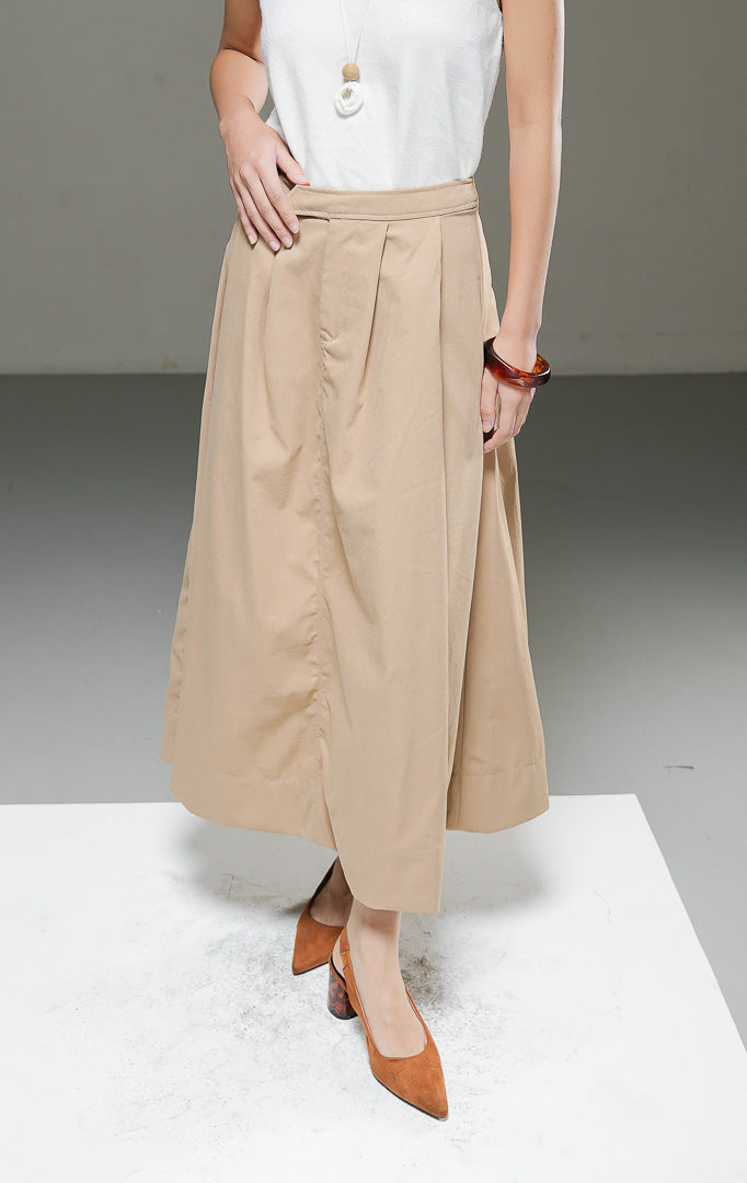 Rok midi wanita Gracelyn Skirt warna light brown cokelat muda model A-line high waist dengan detail lipat pleat di depan dan kantong samping.
