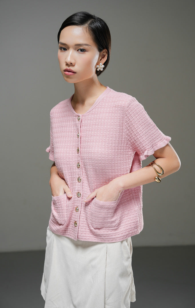 Outer rajut pendek wanita Henley Outer warna pink lengan pendek dengan tekstur motif, kancing depan warna emas, dua saku depan, dan detail ruffle hem.