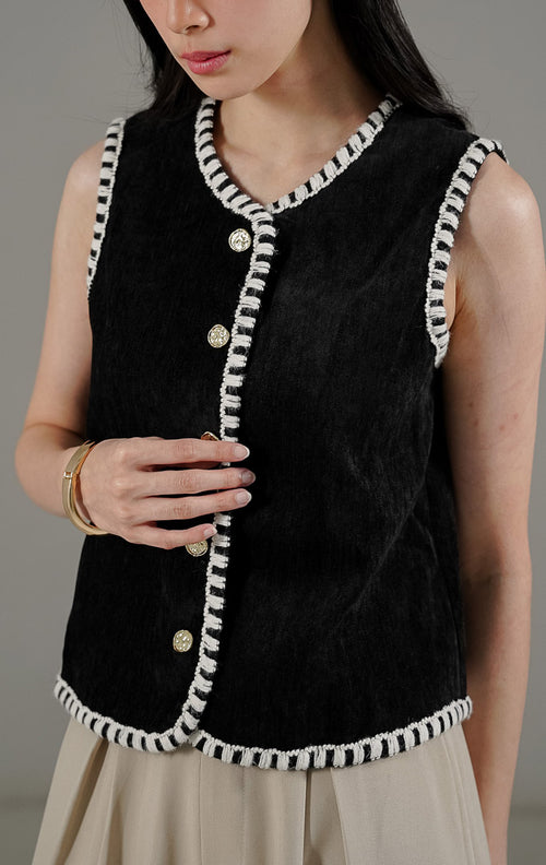 Vesta Vest Black dari This Is April, rompi tanpa lengan wanita warna hitam bertekstur dengan detail jahitan tepi kontras warna putih dan kancing emas