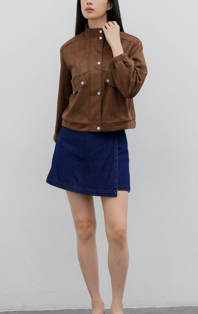 Jaket wanita warna cokelat tua (dark brown) Honoria Jacket berbahan campuran crinkled cotton-nylon dengan kerah tinggi (high-neck), bukaan kancing jepret (snap-button closure), dan saku fungsional.