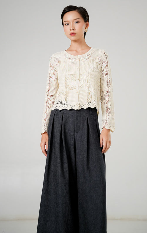 Atasan rajut kardigan wanita Inara Ivory dengan motif rajut pointelle (berlubang halus), kancing mutiara kecil di bagian depan, kerah bulat, dan lengan panjang dari This Is April.